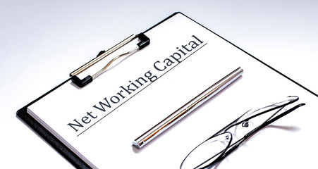 Paper with Net Working Capital on a table with glasses and pen