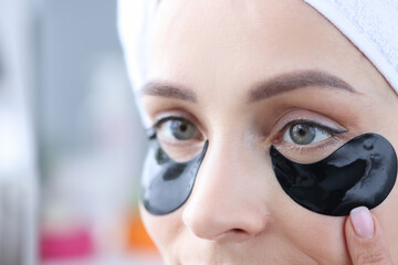 Woman uses black patches under eyes to eliminate swelling and smooth wrinkles