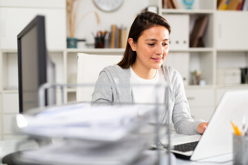 Confident female business consultant sits at her workplace in the office in front of a laptop