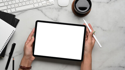 Above view of woman holding digital tablet with blank screen and stylus pen on marble background.