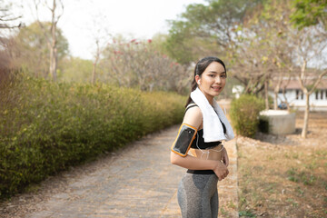 Healthy young woman with earphones standing in park after work out.