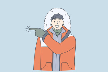 Adventurer, expedition, winter traveling concept. Young happy frozen man in warm clothes cartoon character having fun during winter pointing away with finger wearing gloves and warm clothes 