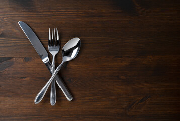 Spoon, fork, and knife on a wooden table.