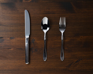 Spoon, fork, and knife on a wooden table.