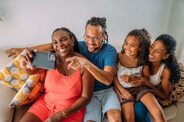 Happy Latinx family making a video call on their cell phone - obrazy, fototapety, plakaty