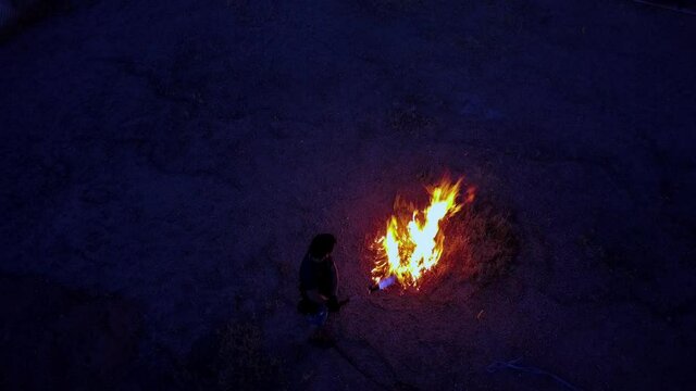 Flamethrower igniting brush, top-down at 10 degree angle. Dark nondescript male subject