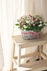 Flowers bouquet in basket against curtains