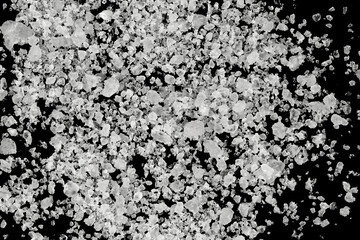 Pieces of  white sea salt on a black background. clear crystalline pebbles. white ice cubes
