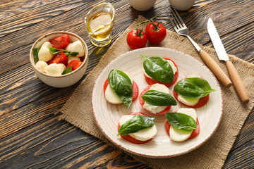 Composition with mozzarella cheese, tomatoes and basil on wooden background