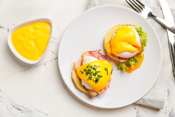 Plate with tasty eggs Benedict on light background