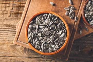 Rolgordijnen Bowl with sunflower seeds on wooden background © Pixel-Shot