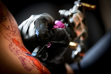 Obraz na płótnie Canvas Female tattoo artist making tattoo on a men’s arm