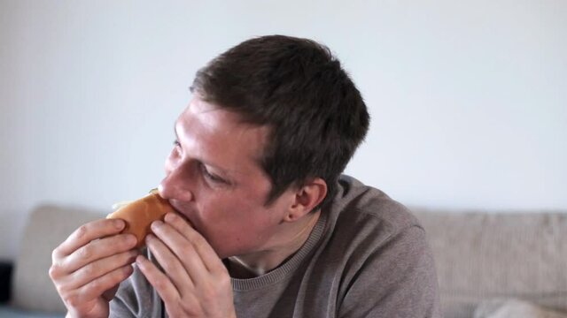 The man is eating a hot dog. Eating foods high in carbohydrates
