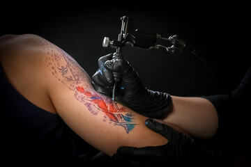 Female tattoo artist making tattoo on a men’s arm