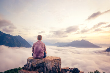 Man sitting on a summit with a beautiful view over the clouds