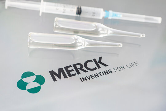 Vials of liquid on a white table and the logo of a large pharmaceutical company.