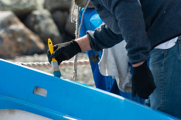 a man painting a boat with blue paint - 422231510