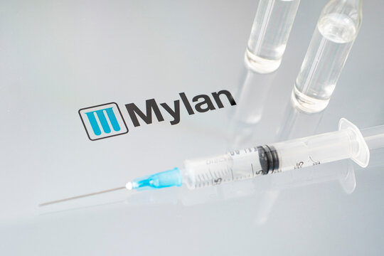 Vials of liquid on a white table and the logo of a large pharmaceutical company.