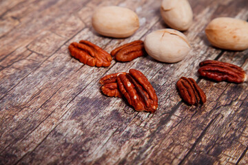 Whole and opened pecan nuts on textured wooden background. Front and top view, close-up. Copyright space for website or logo