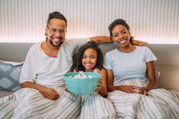 cheerful latinx family eating popcorn watching tv at home