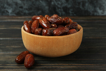 Bowl with dried dates on wooden table