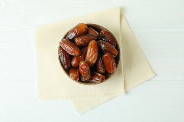 Bowl with dried dates on kitchen napkin on white wooden table