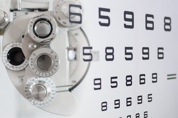 Close up of phoropter eyesight measurement testing machine with double exposure test chart vision optician check up number, Eye health check and ophthalmology concept.