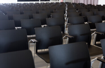 Rows of black plastic chairs in conference hall