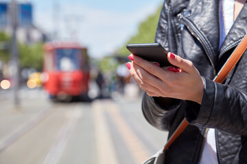 Woman using cellphone on a tram station in Europe.