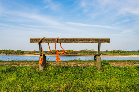 A bench with a view towards the River Rhine on the dyke in Orsoy, North Rhine-Westphalia, Germany