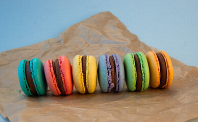 Multicolored macarons with wrapping craft paper on a gray background.