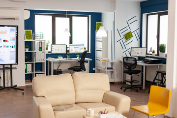 Interior of empty creative office with dusky light, new business, start up company with no people in it. Modern design and confortable couch with nobody in it, place of work startup