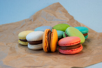 Multicolored macarons with wrapping craft paper on a gray background.
