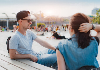 stylish young couple have fun chatting city square summer sunset. happy guy laughs date with girl....