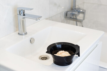 Hair dye on the bathroom sink. Self-coloring hair concept.