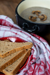 Close-up of a freshly baked bread and a bowl of hot, delicious, healthy, creamy champignon soup. Vertical