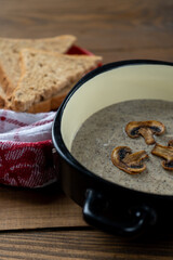 Close-up of a bowl of hot, healthy, creamy champignon soup with freshly baked bread. Vertical