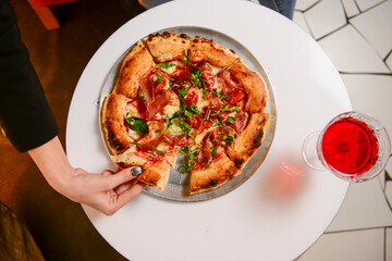 Image of young woman hand taking slice of pizza in restaurant or diner during Christmas holidays.