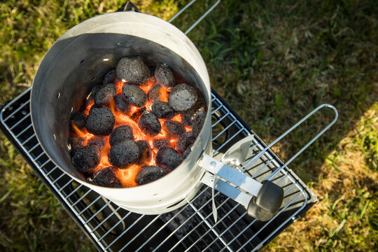 Kohle von Holzkohlegrill brennt mit Feuer und Anzünder im Anzündkamin zum Anheizen für Grill 