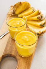 Mango with pineapple smoothie in jug and glasses. Fresh morning breakfast on the table for slimming with yellow fruit