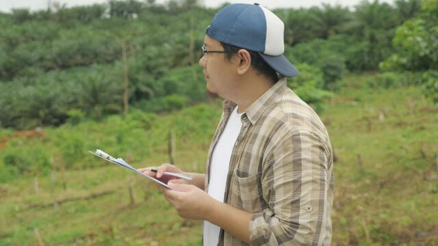 Asian man environmentalist researcher doing work in nature, making writing documentation of his research