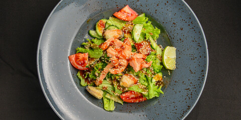 Tuna and vegetable salad in a plate over black background. Healthy food, eating out concept.