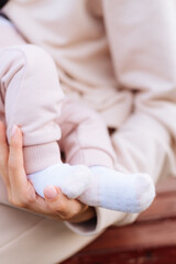 Baby's legs and mother's hands close up