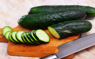 Image of cut fresh cucumbers on wooden table in home kitchen