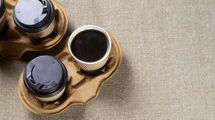 Two disposable paper coffee cups with lids in a cardboard holder