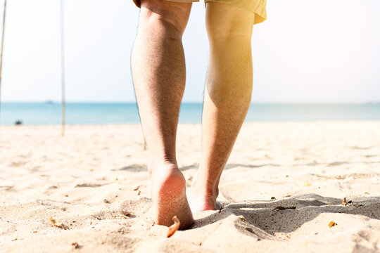 Man leg walking on the sand on the beach