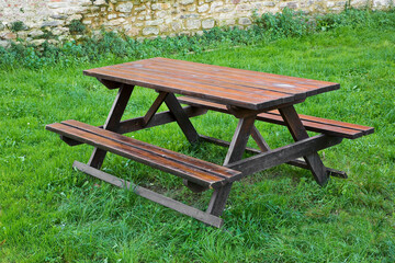 Wooden empty  picnic table on a green meadow of a public park