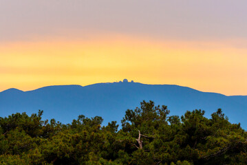 Colorful sunset sky over silhouette of black forest hills and mountains nature landscape in red, orange and blue colors in autumn season