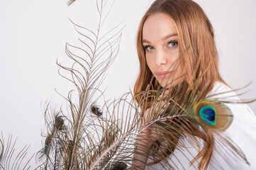 Naklejka premium Portrait of young beautiful woman with long hairstyle. Young girl with peacock feathers
