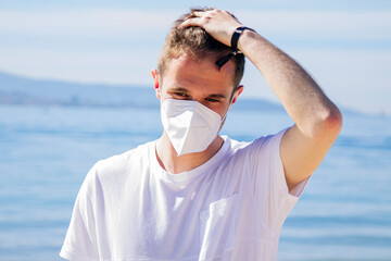 man with medical mask in protection of the coronavirus in the new normal walking on the beach